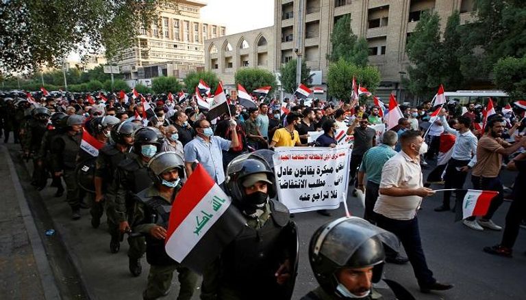 عراقيون يسيرون في بغداد في ذكرى الاحتجاجات المناهضة للحكومة - رويترز