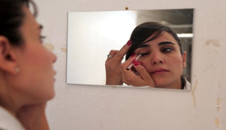 سائقة سيارة الأجرة السورية "كنانة البني" تضع مستحضرات التجميل قبل بدء عملها سائقة سيارة الأجرة السورية كنانة البني