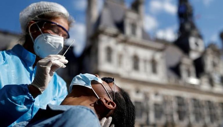 عامل صحي يأخذ مسحة لفحص كورونا من رجل في باريس