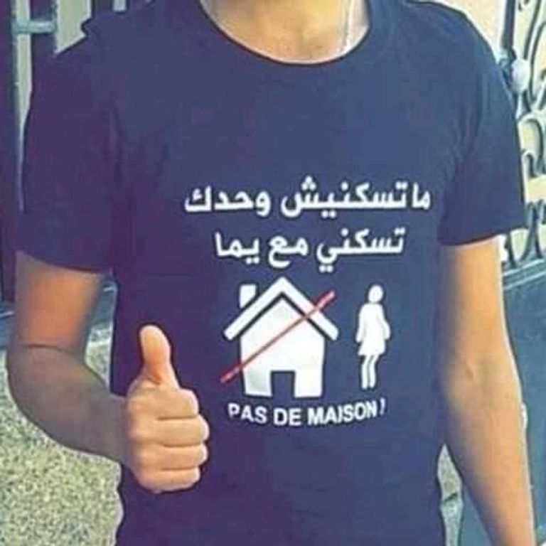 شاب جزائري يرتدي قميص به هاشتاق لا تسكني لوحد بل مع والدتي شاب جزائري يرتدي قميص به هاشتاق لا تسكني لوحد بل مع والدتي