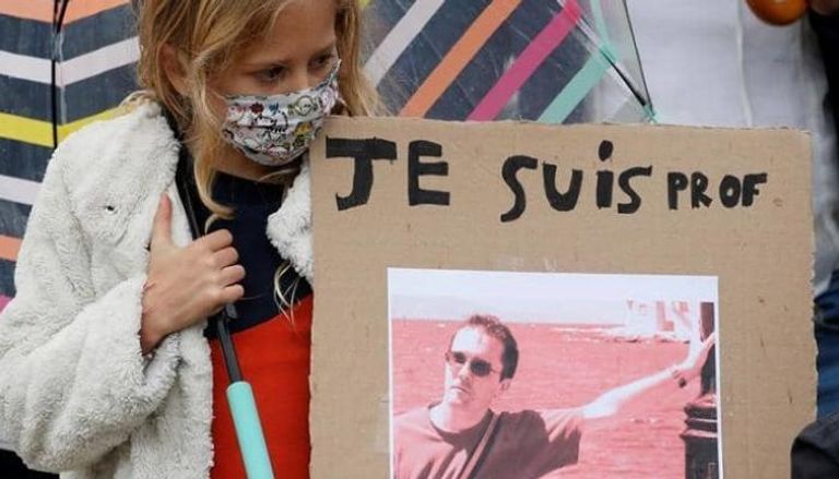 فرنسية تحمل لافتة عليها صورة للمدرس المذبوح