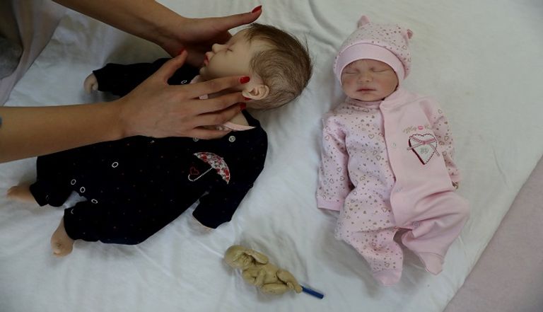 إيرانية تحمل دمية شبيهة بالأطفال