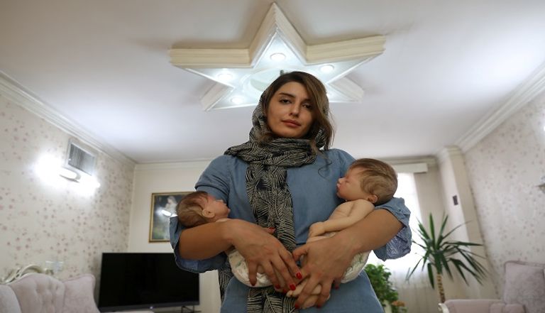 إيرانية تحمل دمية شبيهة بالأطفال