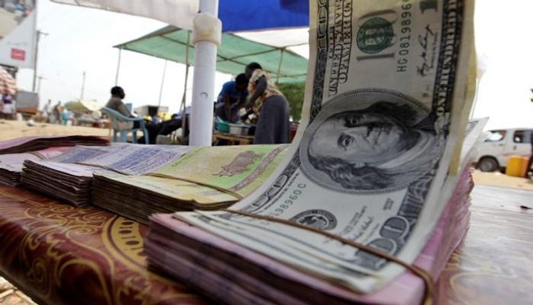 دولارات أمريكية بجوار أوراق نقد سودانية