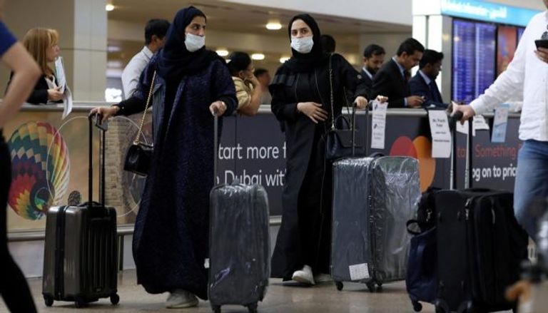 سيدتان تضعان كمامة عند المرور في ساحة مطار عربي