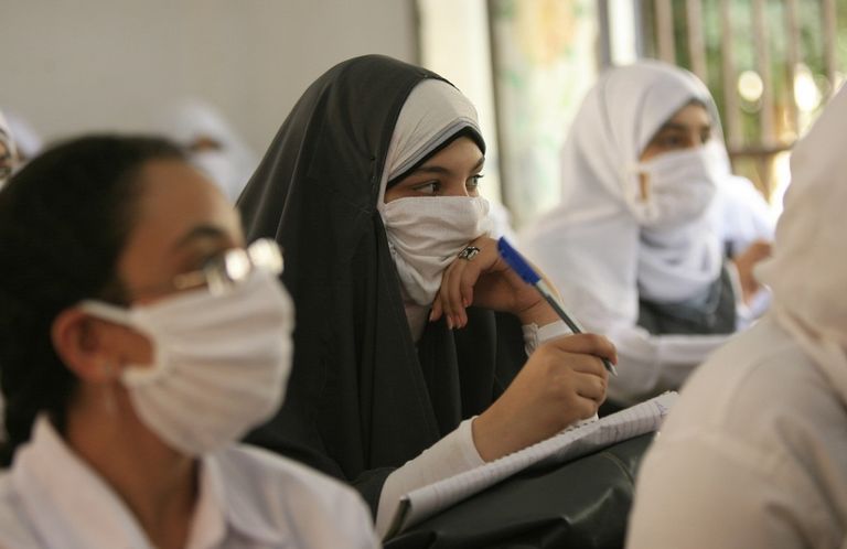 سيدتان تضعان كمامة عند المرور في ساحة مطار عربي