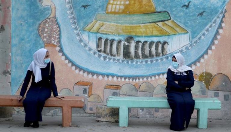 طالبتان ترتديان كمامتين وتحرصان على التباعد في غزة