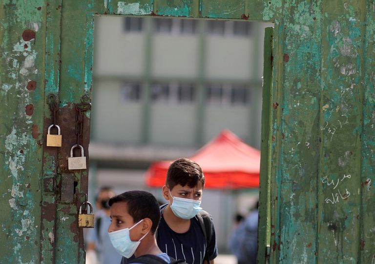 طالبتان ترتديان كمامتين وتحرصان على التباعد في غزة