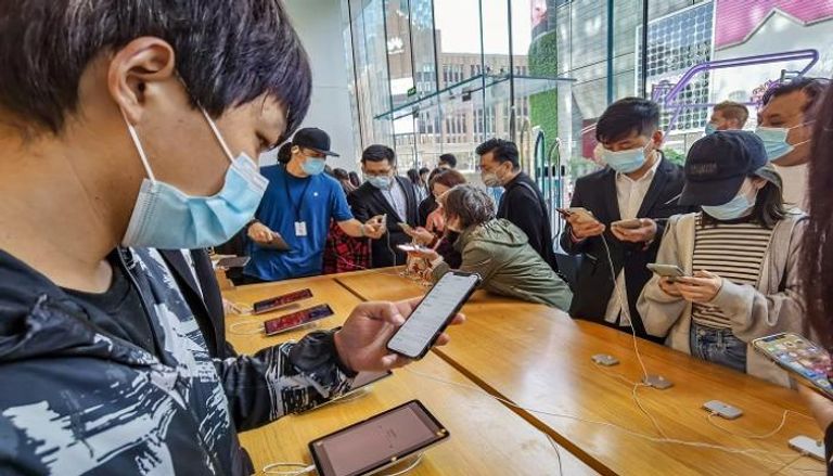 عملاء يجربون هواتف iPhone 12 بمتجر Apple في شنغهاي - أ ف ب
