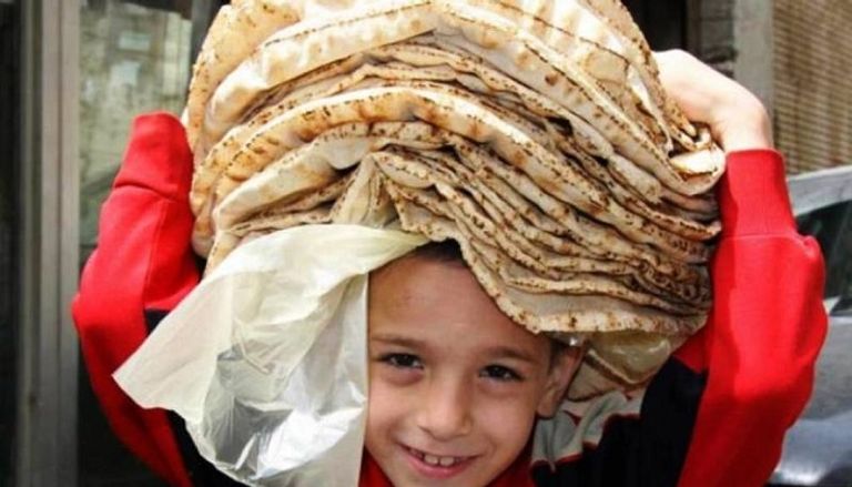 طفل سوري يحمل الخبز على رأسه منفذ لبيع الخبز في سوريا