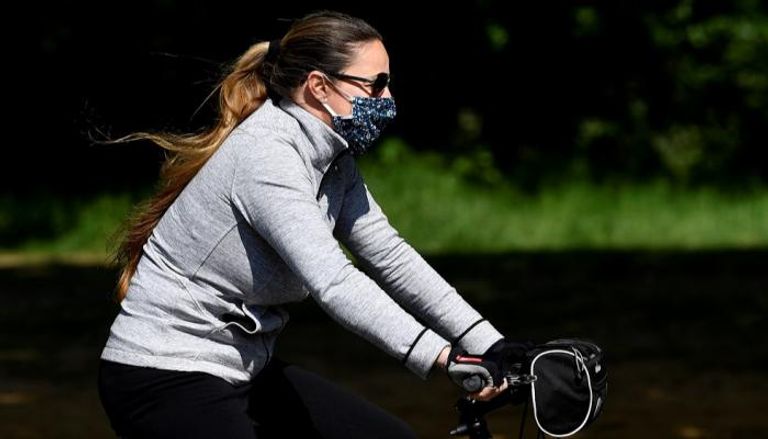 امرأة ترتدي كمامة بينما تقود دراجة في لندن