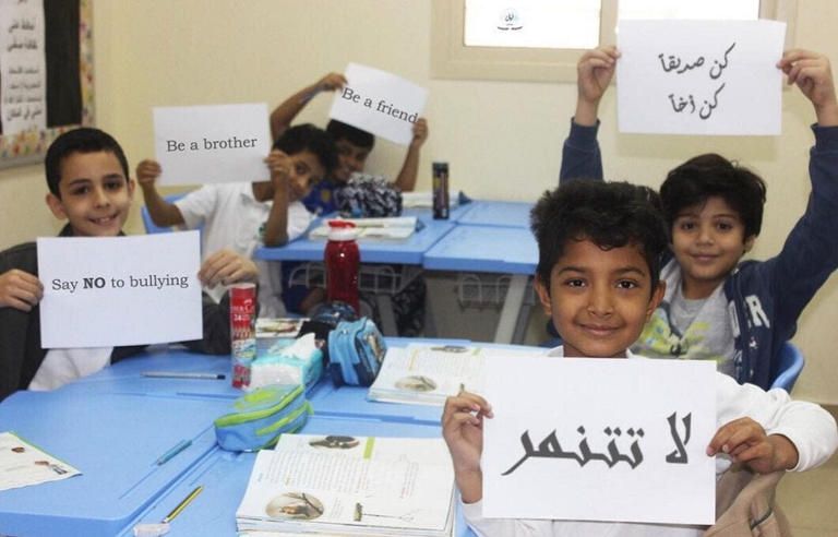 أطفال في إحدى فصول المدرسة ترفع لافتة "لا تتنمر" أطفال يتنمرون على زميلتهم في المدرسة - تعبيرية