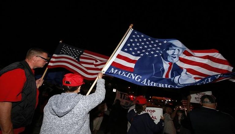 أنصار الرئيس الأمريكي يحملون أعلاما عليها صورته-  أ.ف.ب 