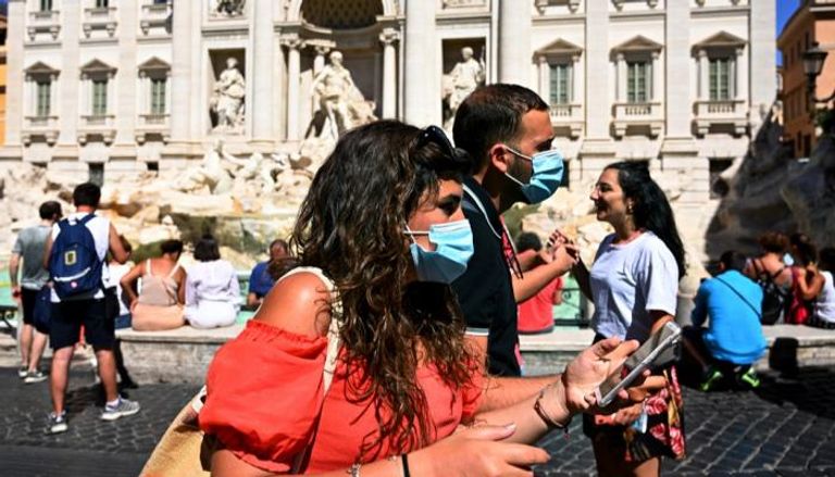 شخصان يرتديان كمامتين للوقاية من فيروس كورونا في إيطاليا