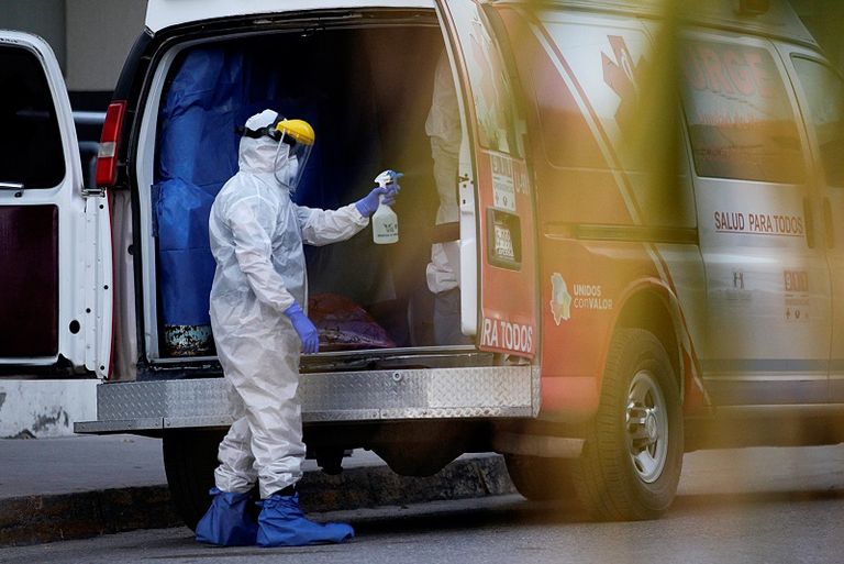 عملية تعقيم سيارات الإسعاف التي تنقل مصابي فيروس كورونا أمريكي يرتدي الكمامة داخل أحد المستشفيات