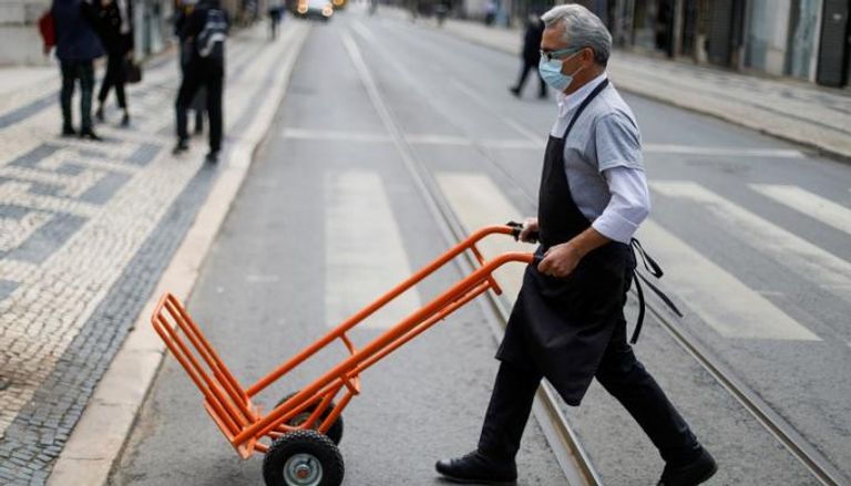 عامل يرتدي الكمامة في أحد شوارع لشبونة