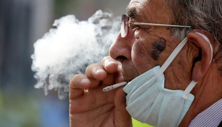 رجل يرتدي كمامة بينما يدخن سيجارة