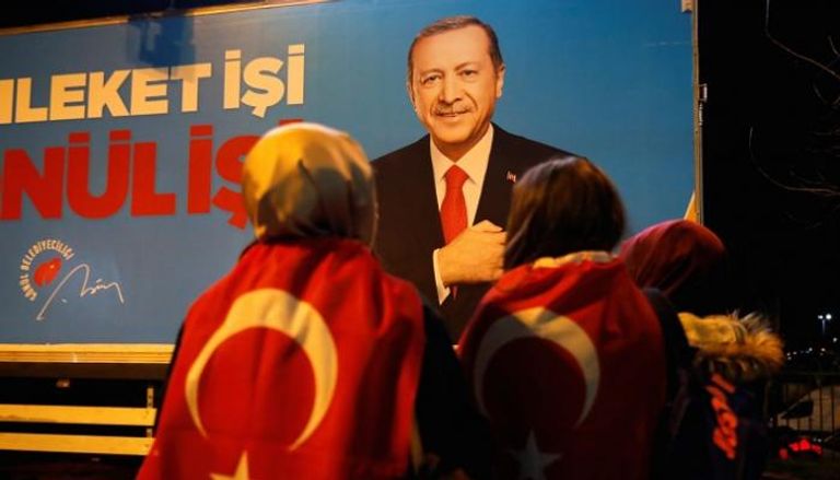 أنصار لأردوغان يقفون أمام لوحة للرئيس التركي - أرشيفية