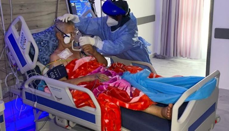 ممرضة تساعد مريضا بفيروس كورونا في ليبيا