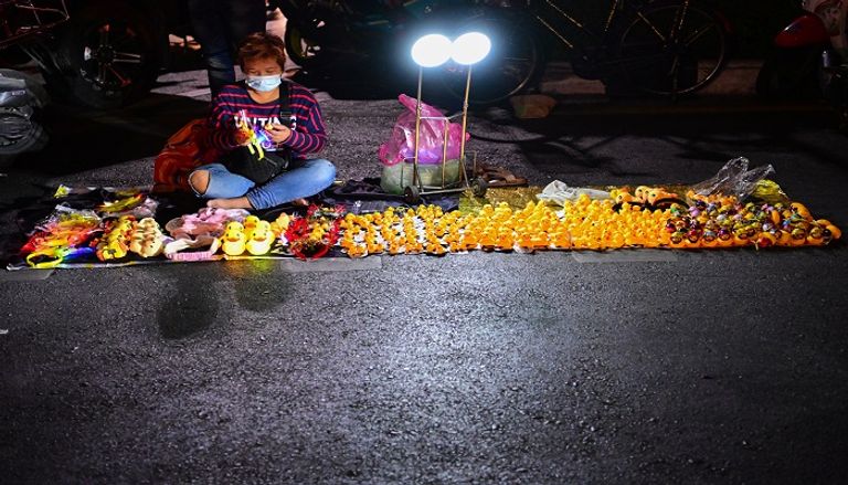 بائعة في تايلاند تبيع رمز الاحتجاجات الجديد- أ.ف.ب متظاهرة في تايلاند ترتدي رمز الاحتجاجات الجديد- أ.ف.ب