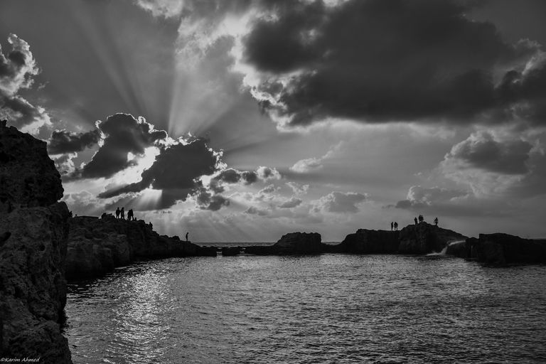 شباب يقفون على صخور البحر في منطقة المنتزه