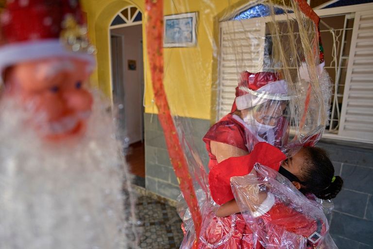 ماما نويل تقبل طفلة من وراء ستار بلاستيكي