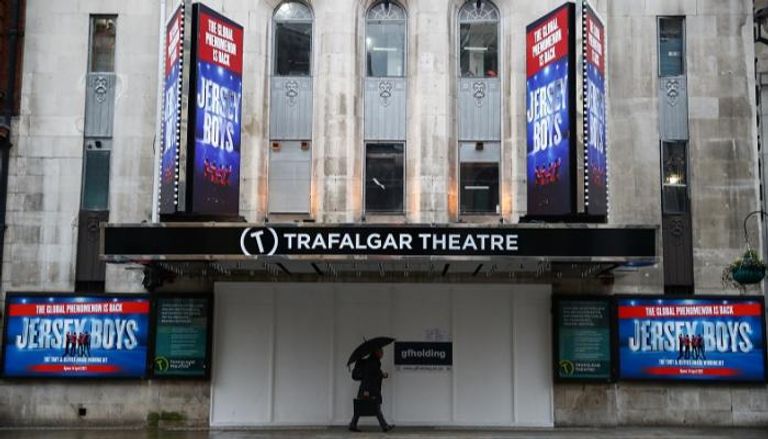 شخص يرتدي الكمامة أمام مسرح ترافالجار في لندن
