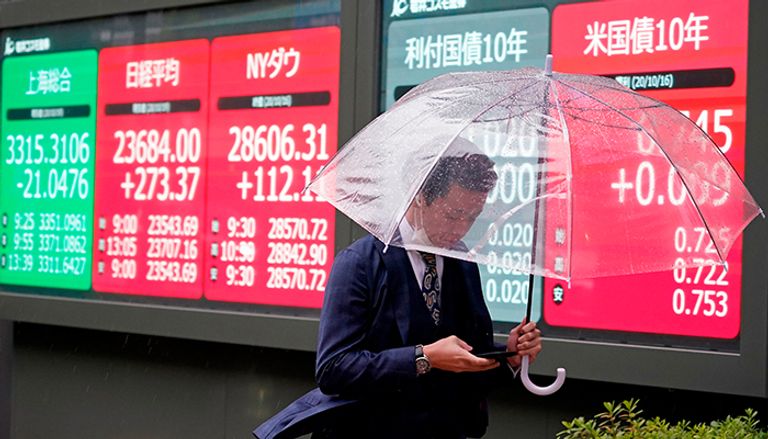 رجل يحمل مظلة ويسير بجوار مؤشر نيكي للبورصة أذكى شعوب في العالم.. معايير وضوابط