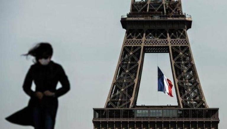فتاة ترتدي الكمامة للوقاية من كورونا، وتسير بالقرب من برج إيفل في العاصمة الفرنسية باريس ارتداء الكمامة يحمي من الإصابة بفيروس كورونا