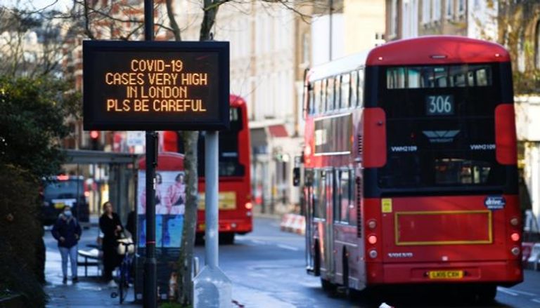 حافلات تمر بجوار لافتة عليها رسالة معلومات عن الصحة العامة