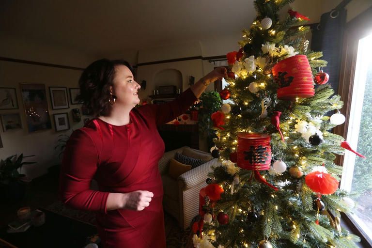 امرأة تقوم بتزيين شجرة الكريسماس للاستعداد للاحتفال برأس السنة 2021 وأعياد الميلاد طفلان يتحدثان مع بابا نويل المحتمي بفقاعة