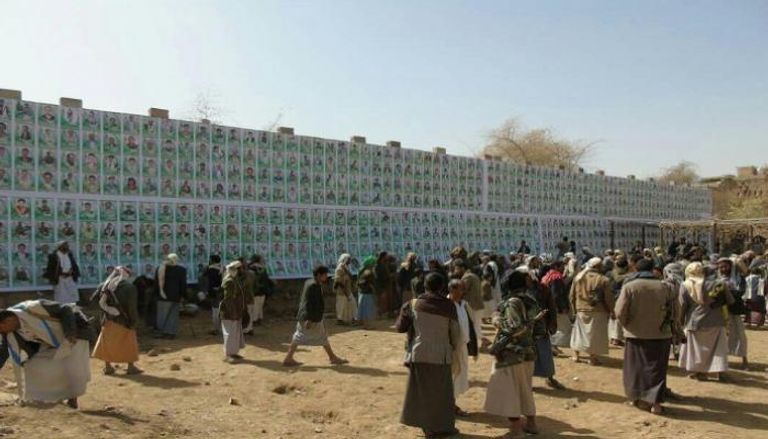 تجمع للحوثيين أمام حائط يحمل صور قتلاهم