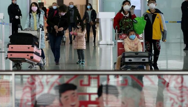 مسافرون يرتدون أقنعة الوجه بمطار بكين الدولي - رويترز