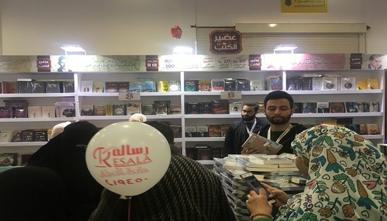 شباب يعملون بأجر للترويج لبعض الكتب بمعرض القاهرة