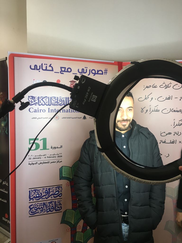 شباب يعملون بأجر للترويج لبعض الكتب بمعرض القاهرة