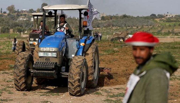 فلسطيني بمساعدة الصليب الأحمريحرث أرضه قرب حدود غزة – رويترز