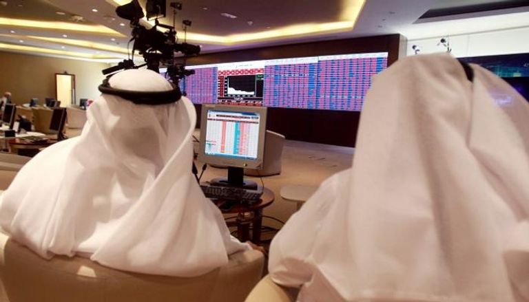 متداولون يراقبون الشاشات التي تعرض معلومات الأسهم في بورصة قطر