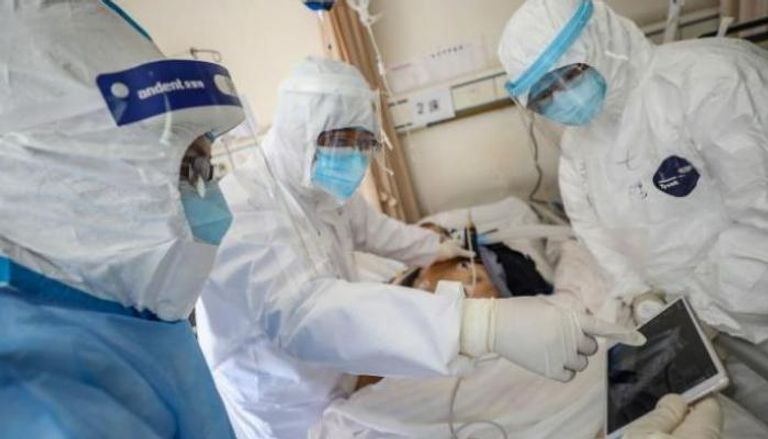 فريق طبي يرتدي الملابس الواقية أثناء الكشف على حالة مصابة بكورونا الجديد