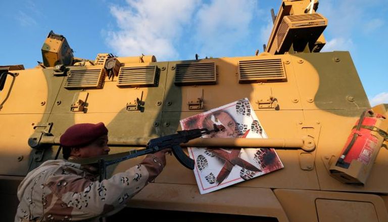 جندي ليبي يصوب سلاحه تجاه صورة لأردوغان - رويترز
