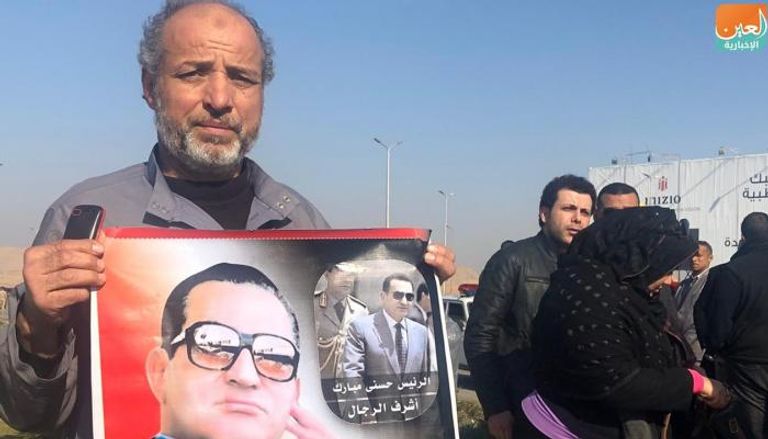 مصري يحمل صورة مبارك أمام المسجد الذي ستقام به صلاة الجنازة
