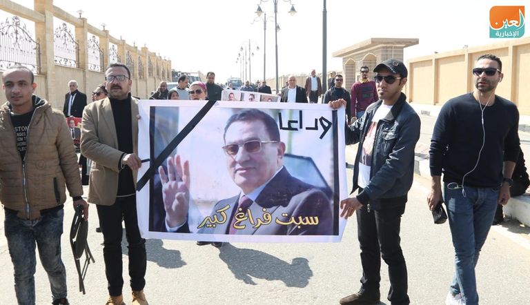 مصري يحمل صورة مبارك أمام المسجد الذي ستقام به صلاة الجنازة