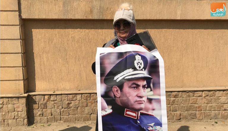 مصري يحمل صورة مبارك أمام المسجد الذي ستقام به صلاة الجنازة