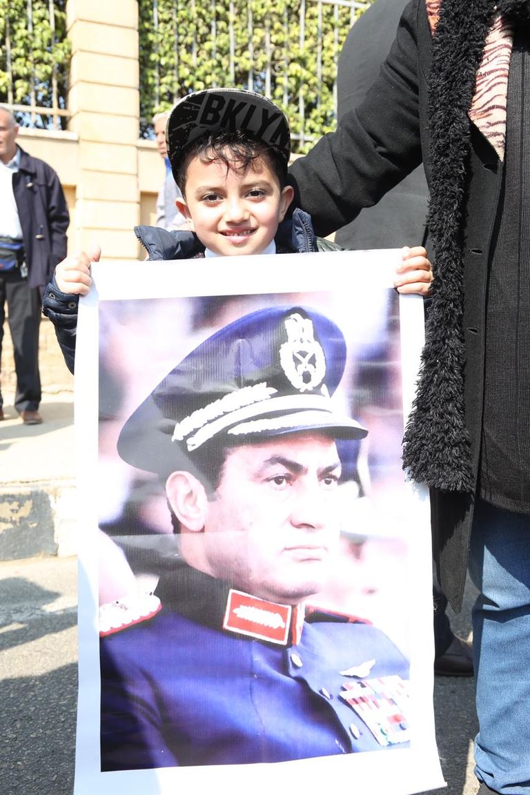 مصري يحمل صورة مبارك أمام المسجد الذي ستقام به صلاة الجنازة