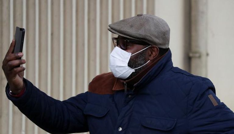 رجل يرتدي الكمامة ويلتقط صورة سيلفي أمام مستشفى كيريل في فرنسا