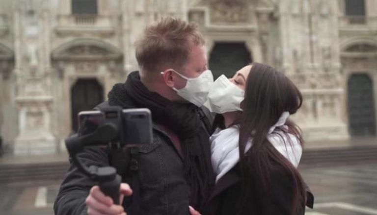 زوجان يبحثان عن قبلة بالكمامات في ميلانو بإيطاليا