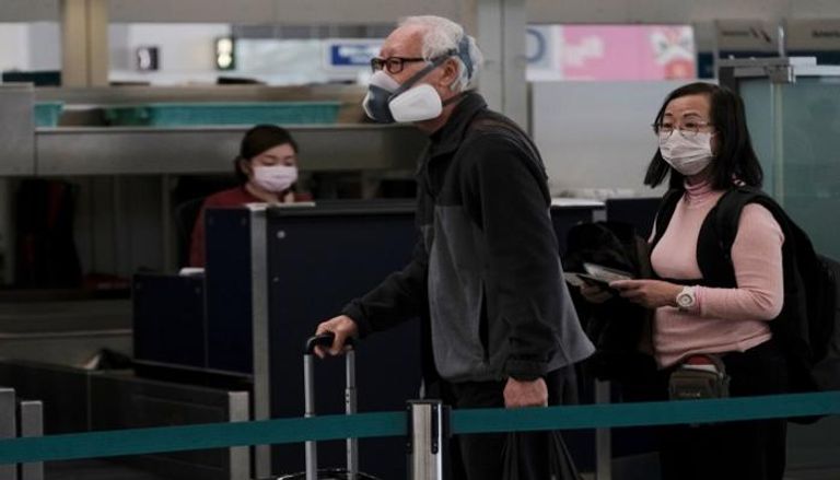 مسافرون يرتدون أقنعة واقية في المطار تجنبا لعدوى كورونا