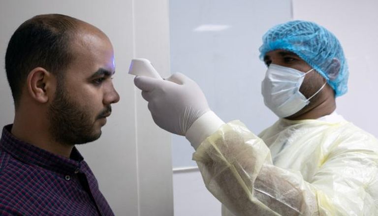 طبيب يجري فحوصات فيروس كورونا على أحد الأشخاص بالكويت