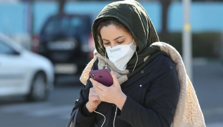 سيدة تسير في الشارع مرتدية الكمامة للوقاية من كورونا