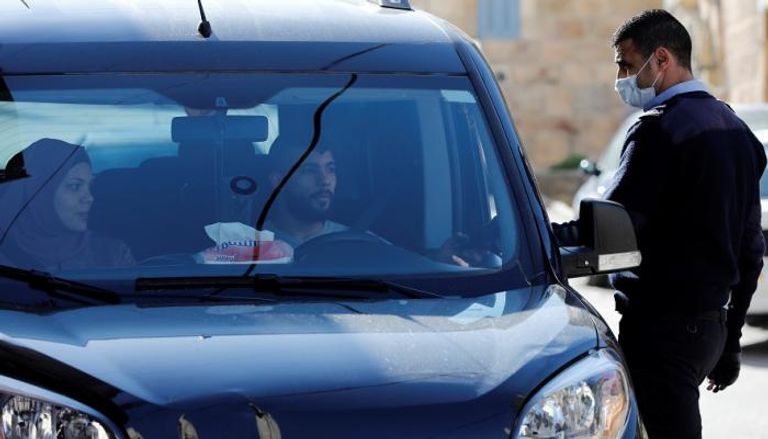 شرطي يرتدي كمامة طبية يستوقف سيارة في أحد شوارع بيت لحم