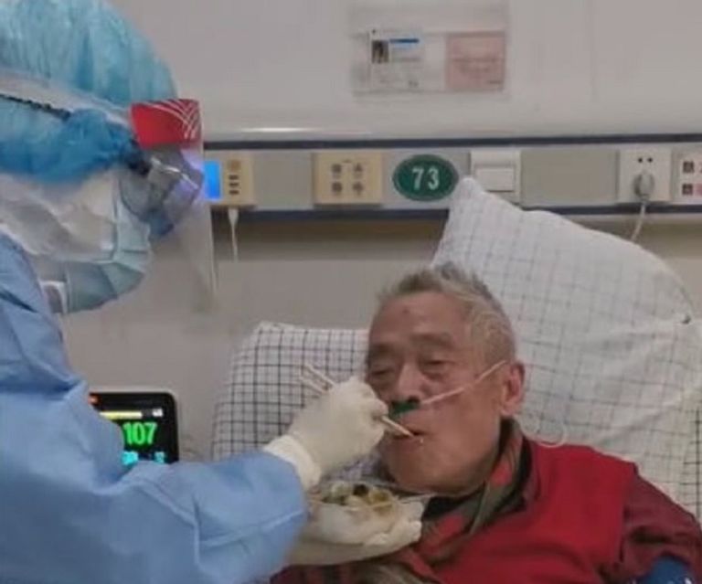 أحد عمال الرعاية الصحية يطعم العالم الصيني خلال فترة وجوده بالمستشفى بعد الإصابة بكورونا الجديد العالم الصيني وزوجته قبل تشخيص إصابتهما بـ"كوفيد-19"